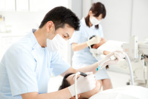 歯科医院で歯科医師や助手が治療している
