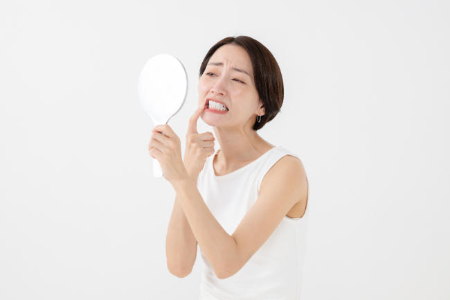 歯周病になっていないか鏡でチェックする女性