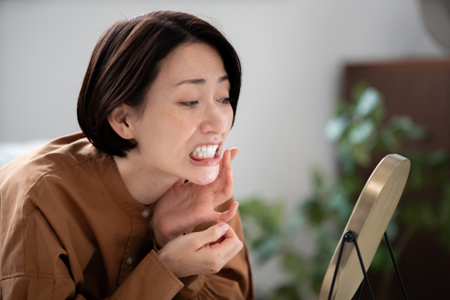 歯茎の状態が気になって鏡を見ている女性