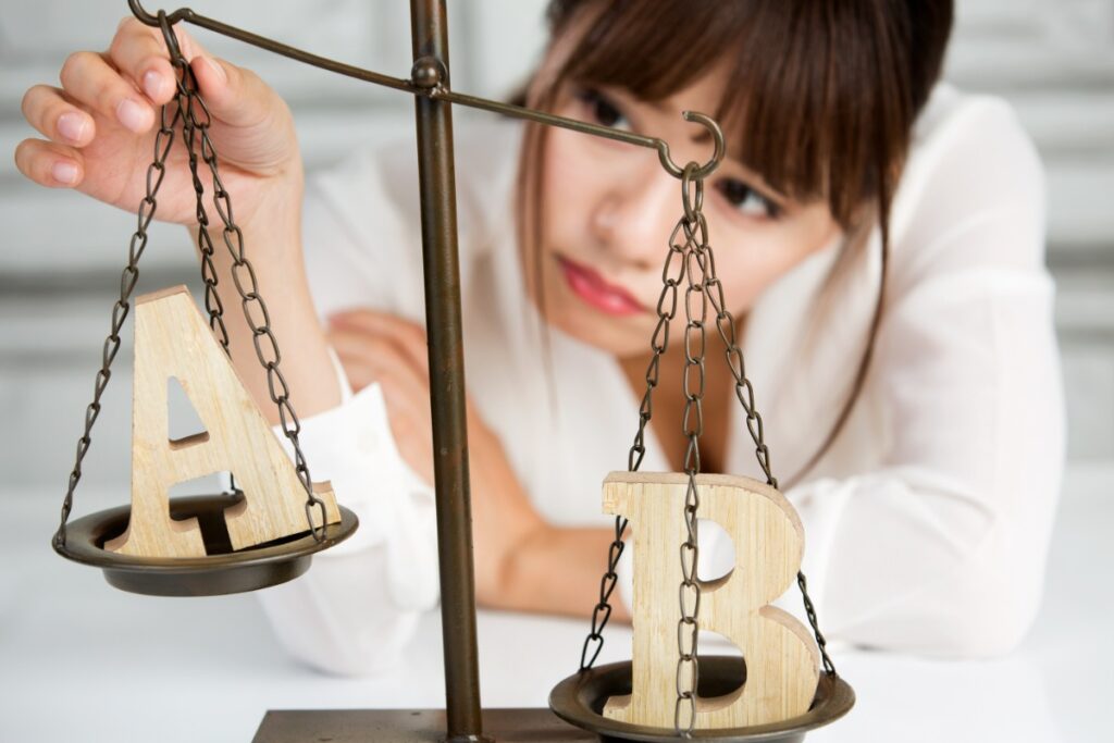 天秤でAとBを比較する女性
